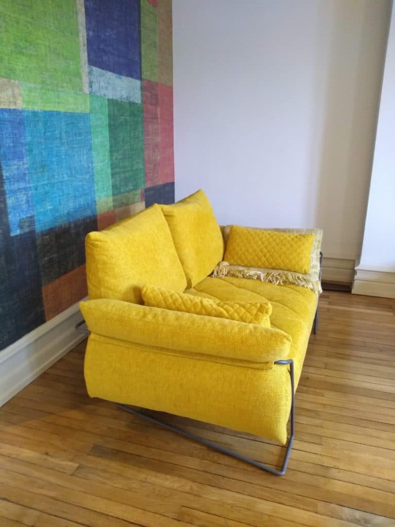 Canapé jaune devant mur de papier peint